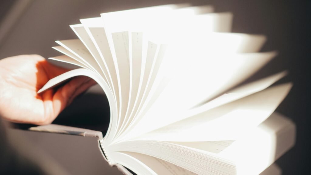 Dynamic photo of hands flipping through book pages with bright lighting and soft focus.